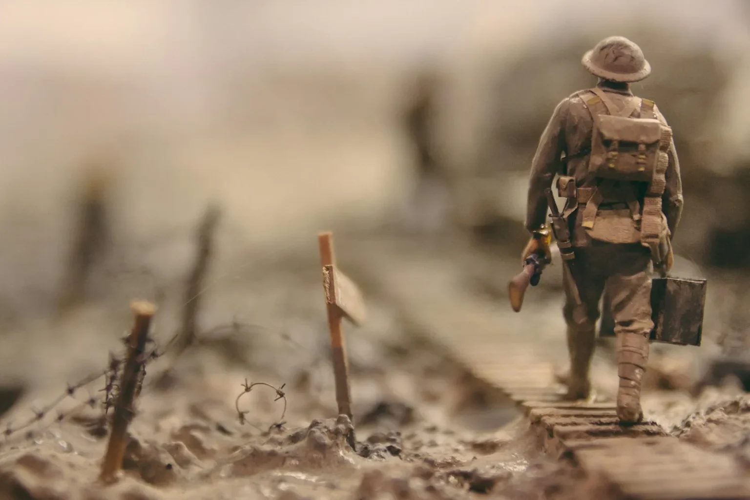 soldier walking on wooden pathway surrounded with barbwire selective focus photography