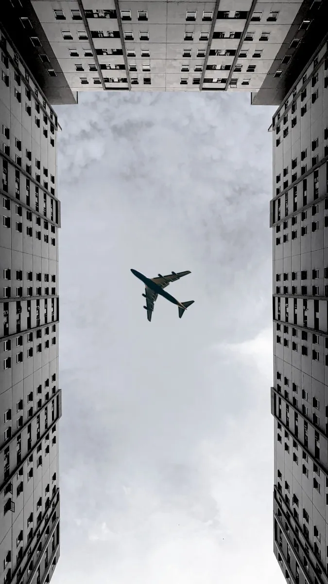 airplane flying over the building during daytime