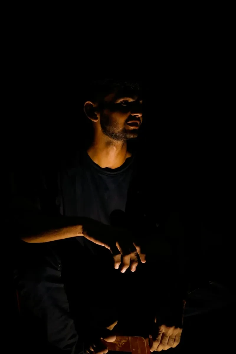 a man sitting in the dark holding a cell phone