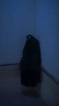 person in black robe standing beside white wall
